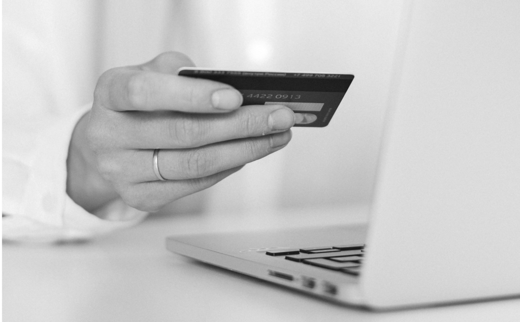 This image introduces our topic of fake online shopping websites, showing a woman's hand holding her payment card in front of a computer.