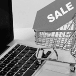 This image of a shopping cart with a sales sign on a laptop highlights the opportunities and scams available on Singles Day.