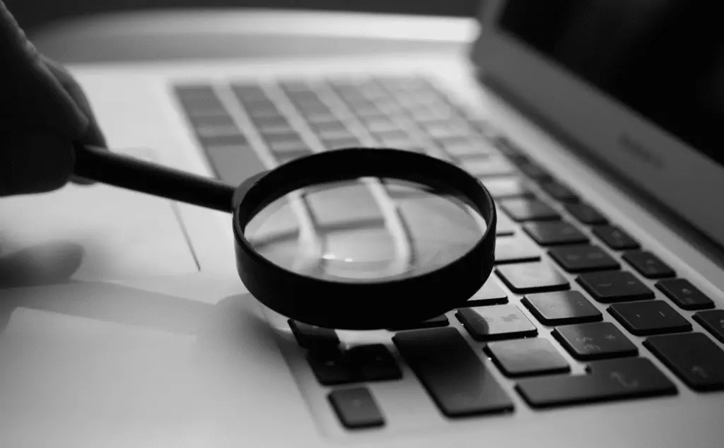 This image of a magnifying glass on a keyboard illustrates our discussion of cybersecurity.