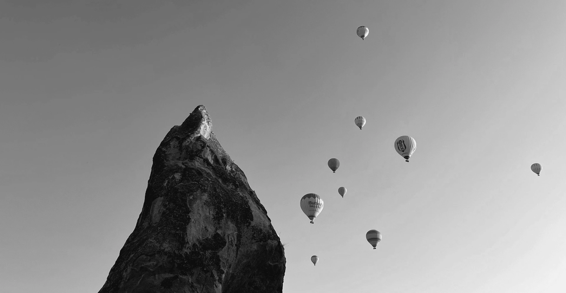 This image of a seven hot air balloons in flight next to a mountain peak illustrates our discussion about launch day scams and frauds, and how to tackle them.